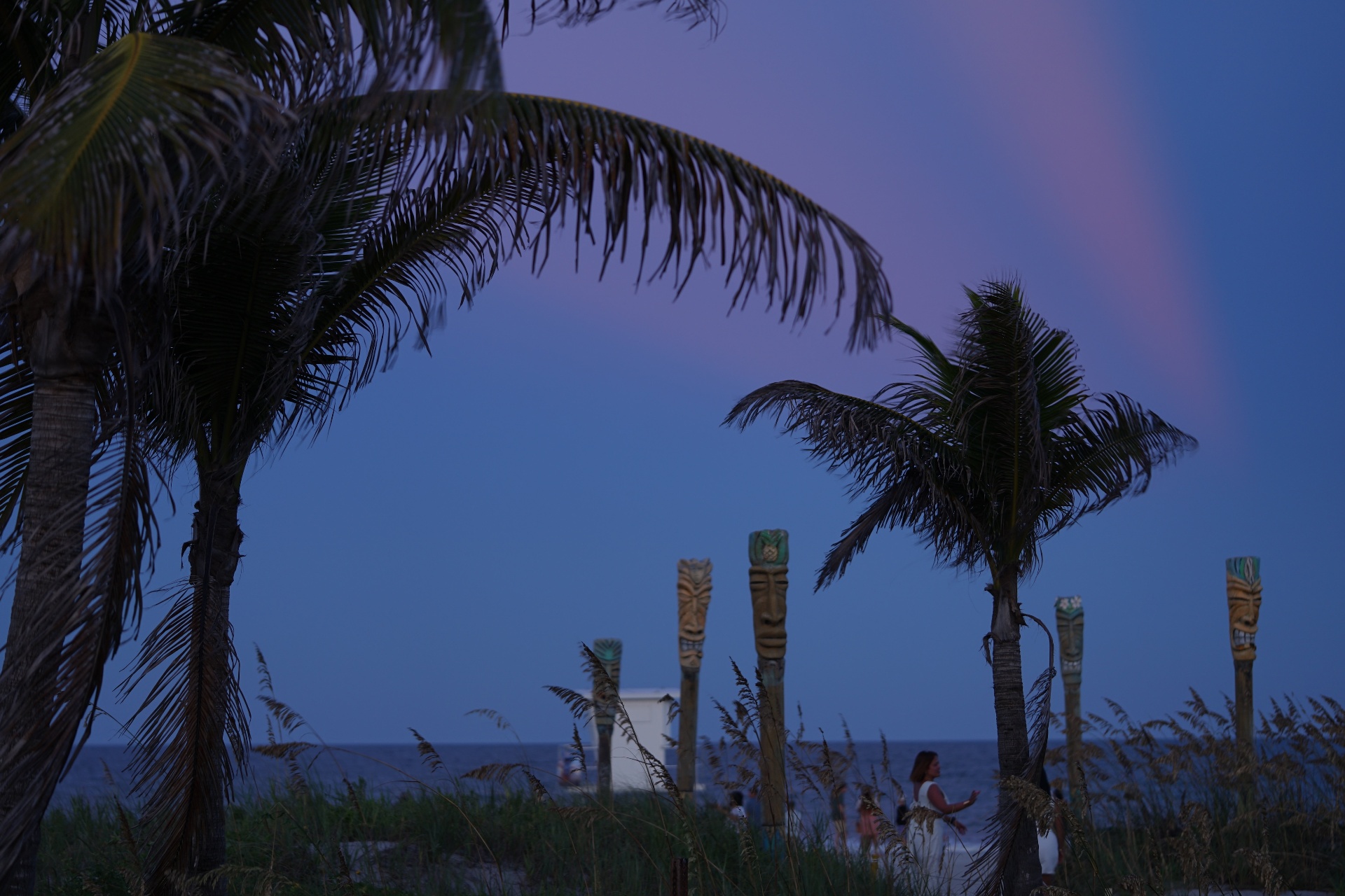 Coconut palms and tiki totems silhouetted at dusk on Cocoa Beach